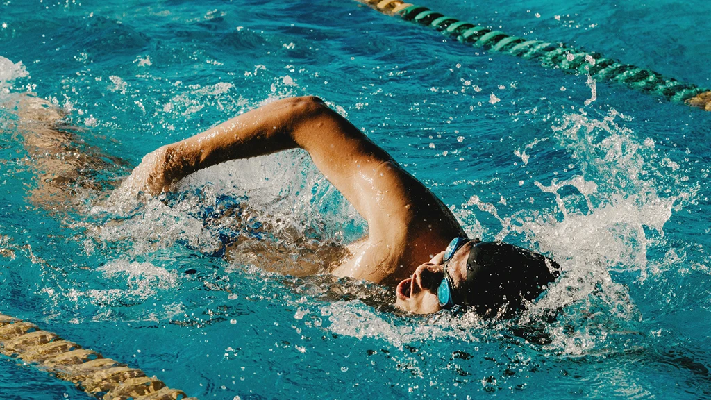 Simmare utför crawl i simbassäng med tävlingsbanor