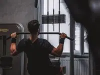 Person tränar med vikter i gym med industriell inredning och stora fönster