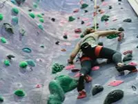 Klättrare på färgglad klättervägg med rosa och gröna grepp