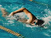 Simmare utför crawl i simbassäng med tävlingsbanor